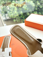 Hermes ladies' slide sandals close-up with white strap and brown footbed with logo