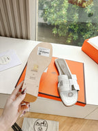 Hermes ladies' slide sandals with white straps and attached label tag