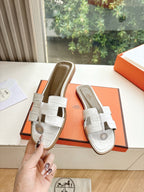 Hermes ladies' slide sandals held in hand, white double straps with round logo emblem