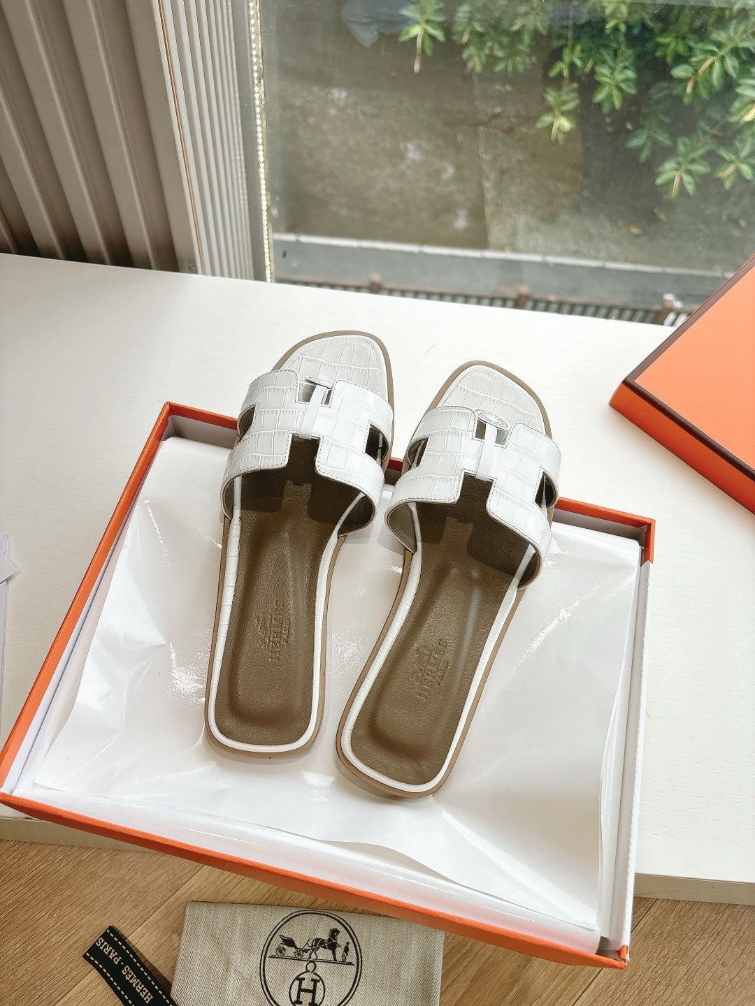 Hermes ladies' slide sandals on display with white straps and round logo on front