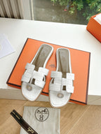 Hermes ladies' slide sandals paired in box with white straps and round logo emblem