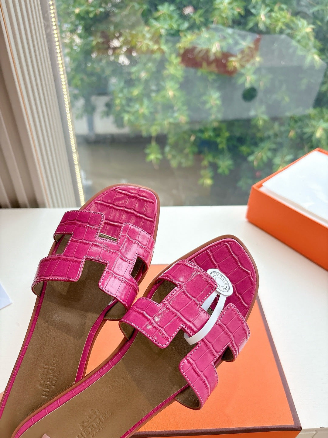 Hermes pink croc-pattern slide sandals, close-up of side straps and buckle