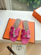 Hermes pink croc-pattern slide sandals, open box shot with two pairs