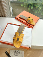 Women’s yellow croc-embossed slide sandals in a box, with cross-strap design