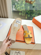 Women’s yellow croc-embossed slide sandals with cross straps, shown on box insert