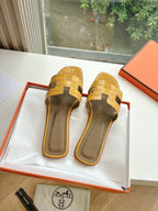 Women’s yellow croc-embossed slide sandals, showing open toe and crossover straps
