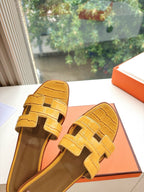 Women’s yellow croc-embossed slide sandals, angled view showing strap and insole