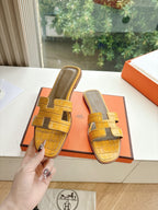 Women’s yellow croc-embossed slide sandals, front view with cross straps and slip-on fit