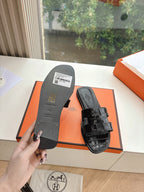 Black slide sandal soles shown, with barcode label and embossed branding on footbed