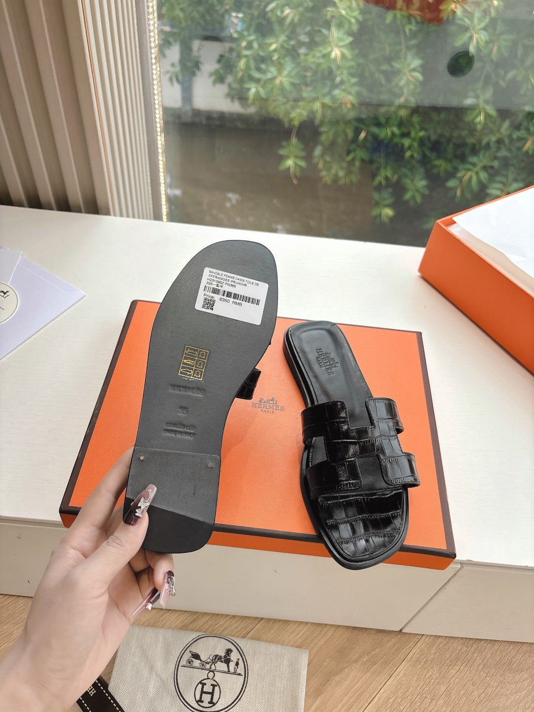Black slide sandal soles shown, with barcode label and embossed branding on footbed