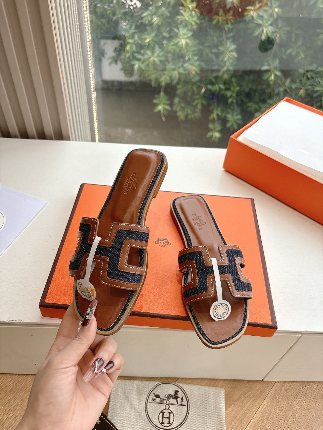 Hermes ladies mule sandals held in hand, brown leather with dark and white patterned band