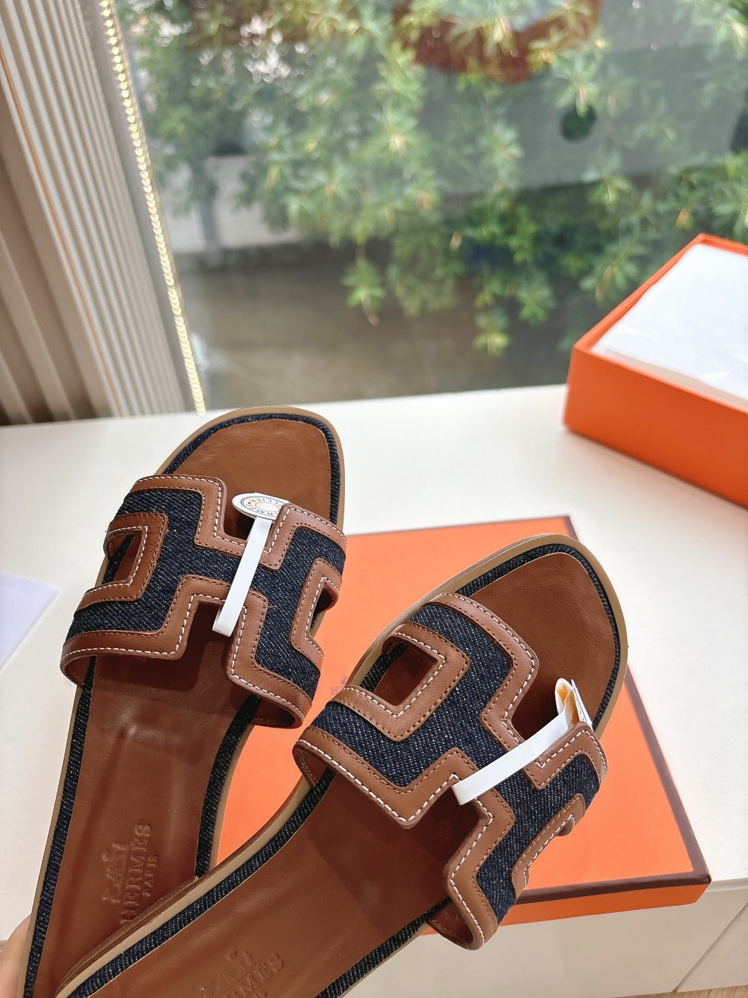 Hermes ladies mule sandals, close side view in brown leather with dark and white trim