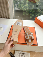 Tan-and-brown leather slide sandals showing sole with size label on orange box