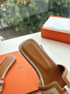 Tan leather slide sandal close-up with geometric trim and logo on footbed