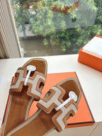 Tan-and-brown leather slide sandals close view of geometric straps and round emblem