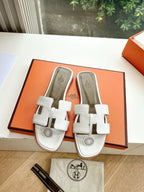 Women’s slide sandals by Hermes, pair of white leather slides with buckle straps