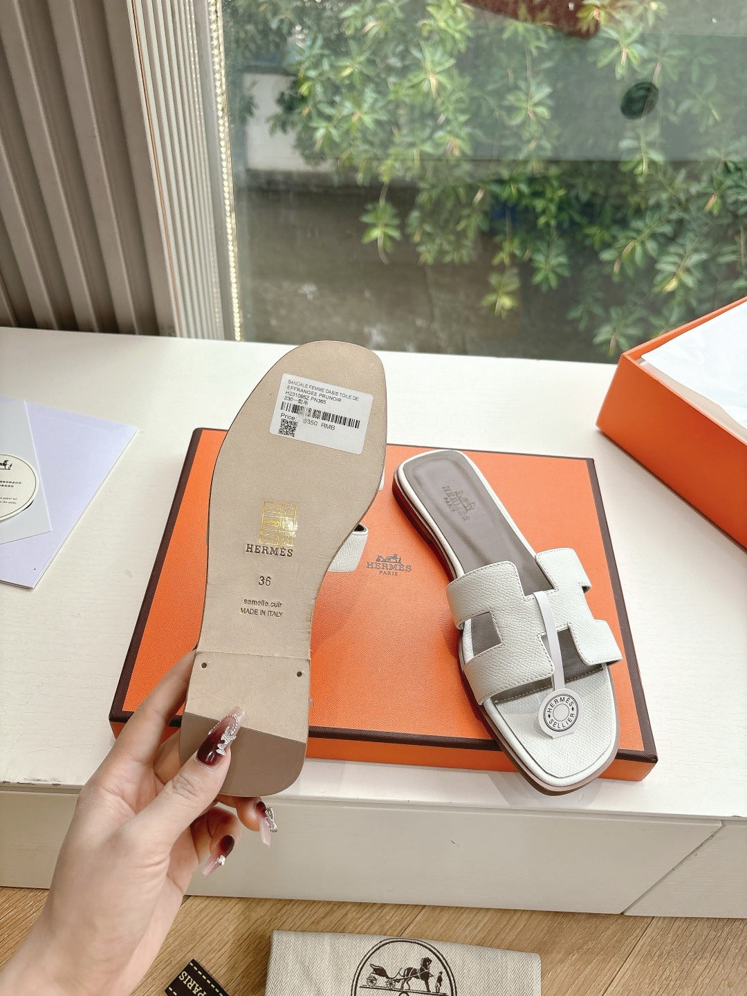 Women’s slide sandals by Hermes, sole and side view of white leather buckle slide