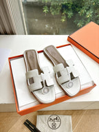 Women’s slide sandals by Hermes, white leather with buckle straps and round logo