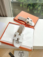 Women’s slide sandals by Hermes, white leather with two strap buckles and round logo