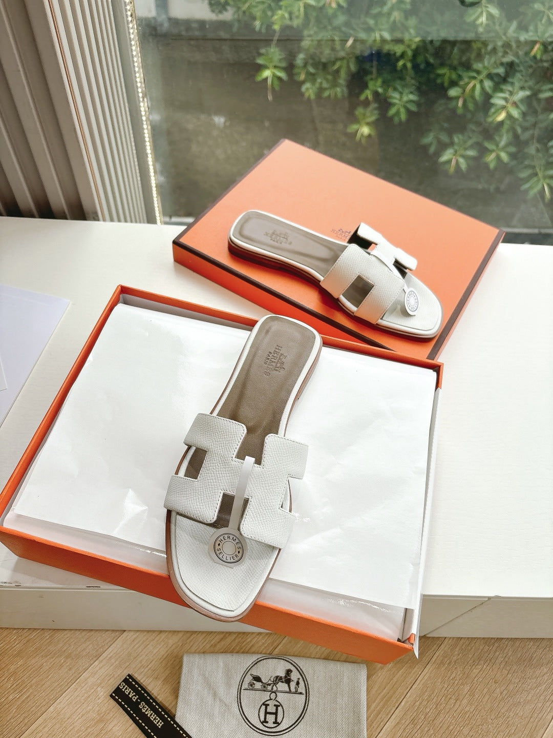 Women’s slide sandals by Hermes, white leather with two strap buckles and round logo