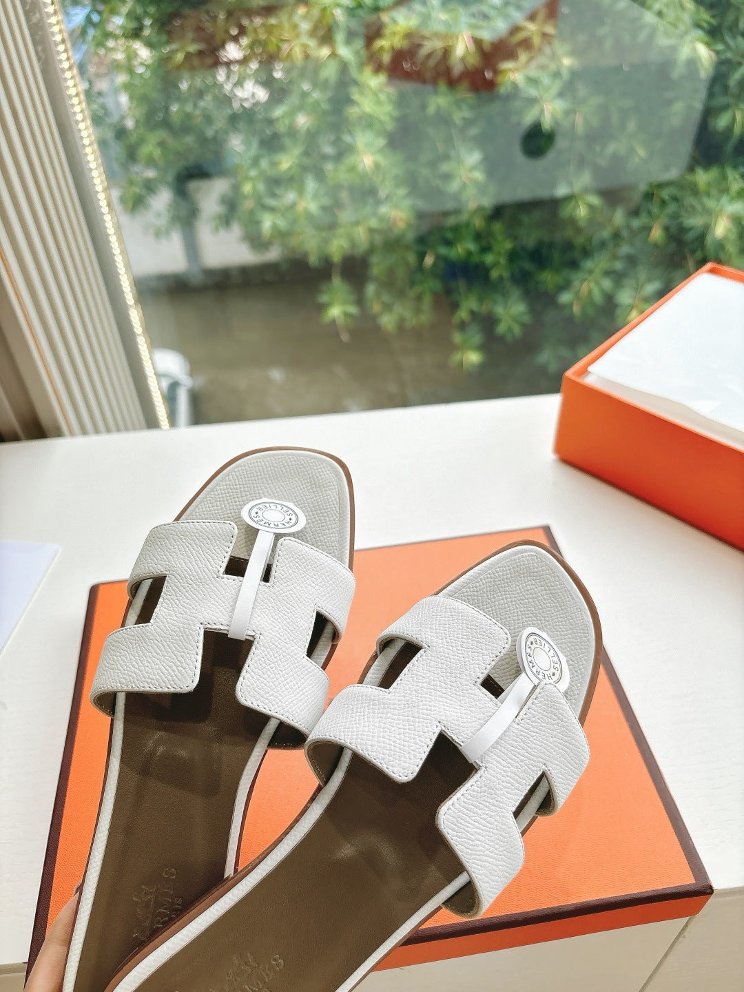 Women’s slide sandals by Hermes, white leather slide with buckle straps and logo badge