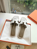Women’s slide sandals by Hermes, white slides with buckle cross straps and round logo