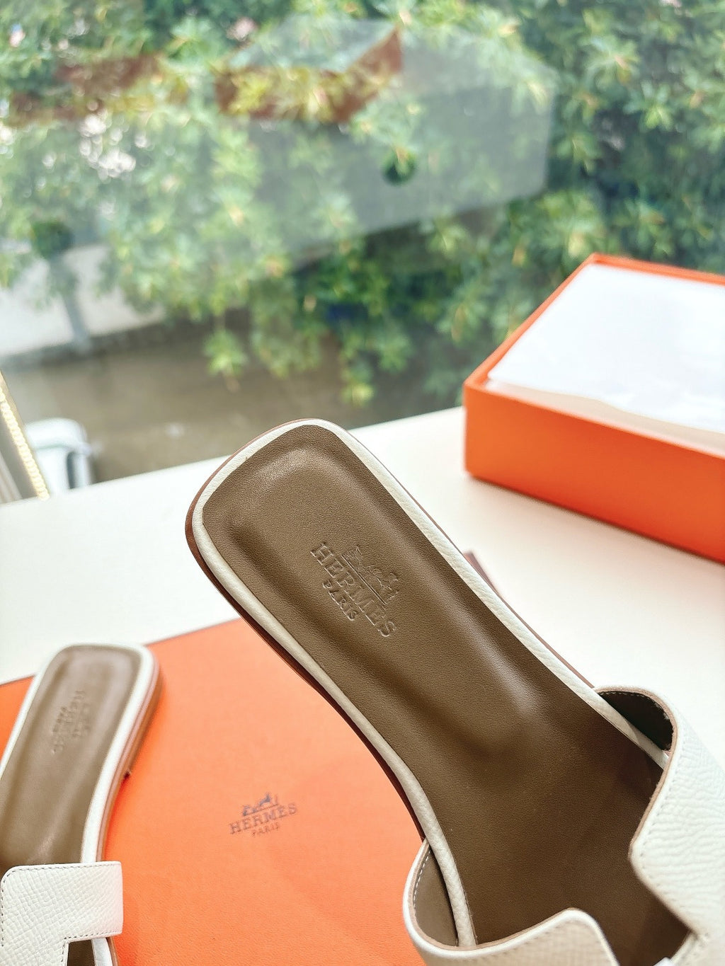 Women’s slide sandals by Hermes, close view of tan insole and white leather slide