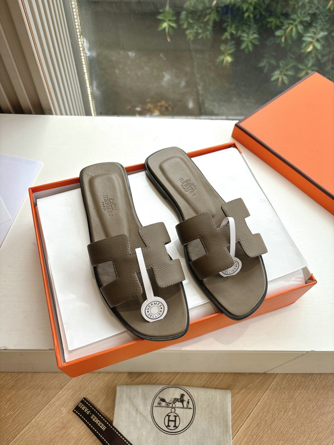 Leather slide sandals in dark taupe with front buckle strap and round logo emblem