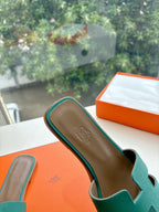 Hermes ladies sandal close-up, teal green slide with H strap and embossed insole