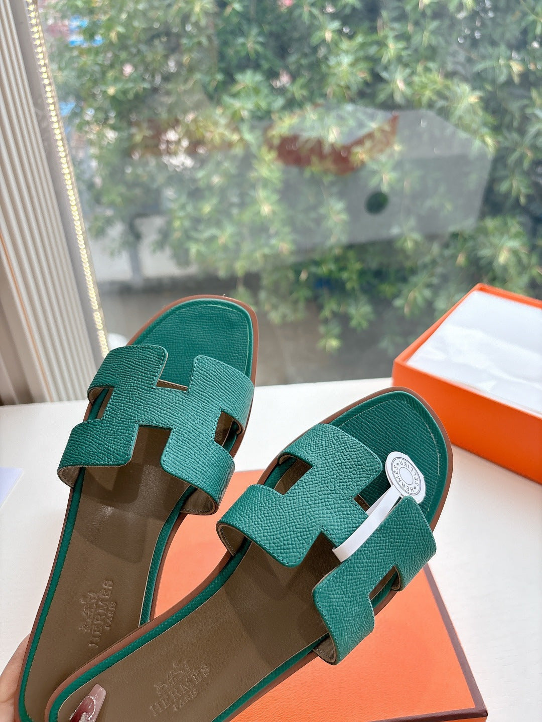 Hermes ladies sandals close-up, teal green H straps with white circular logo patch