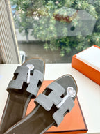 Hermes slide sandals close-up, light gray textured leather and H logo buckle