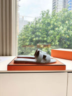 Hermes grey slide sandals displayed on orange shoebox, open-toe single pair