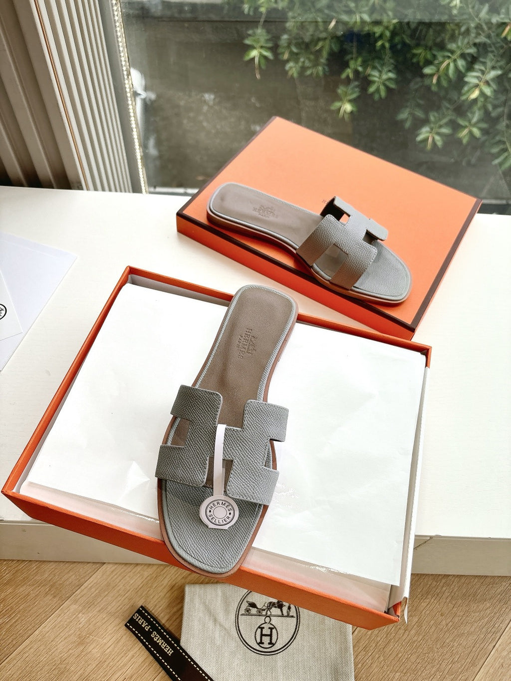 Hermes grey slide sandals in open orange box, two straps with circular logo