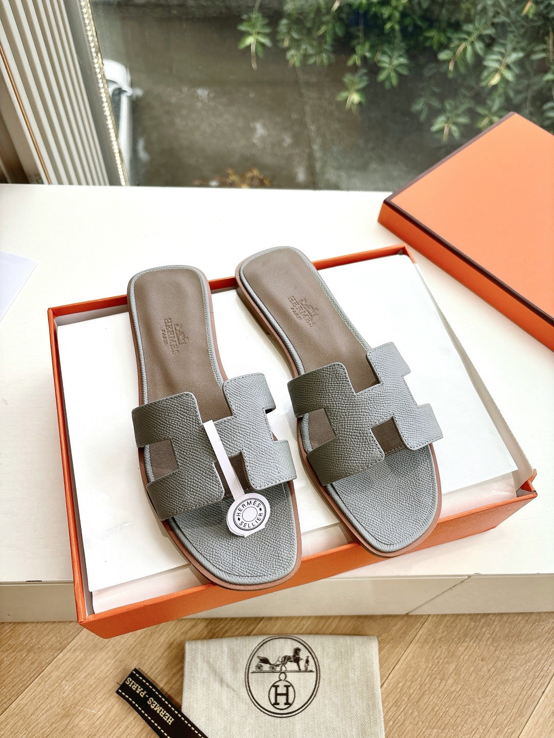 Hermes grey slide sandals with two wide straps and circular logo medallion
