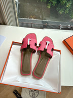 Pink slide sandals with contrasting strap accents and circular logo emblem detail