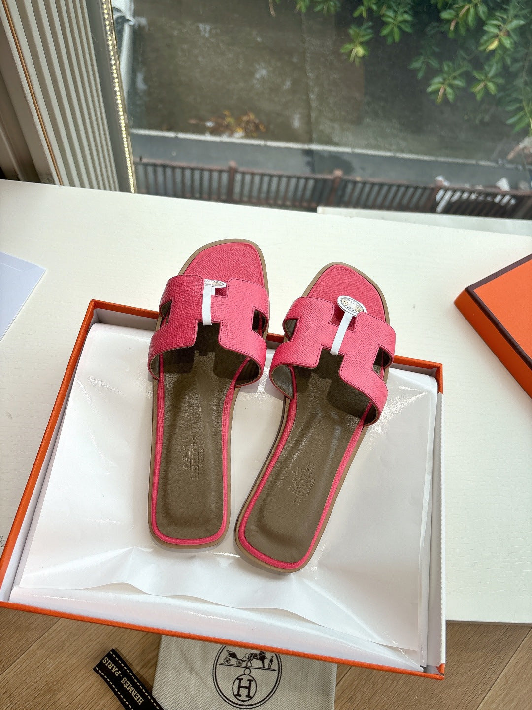 Pink slide sandals with contrasting strap accents and circular logo emblem detail