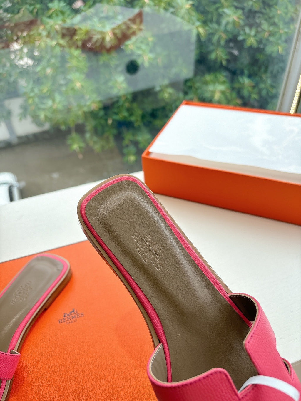Pink slide sandal with cushioned footbed and circular logo emblem edge detail