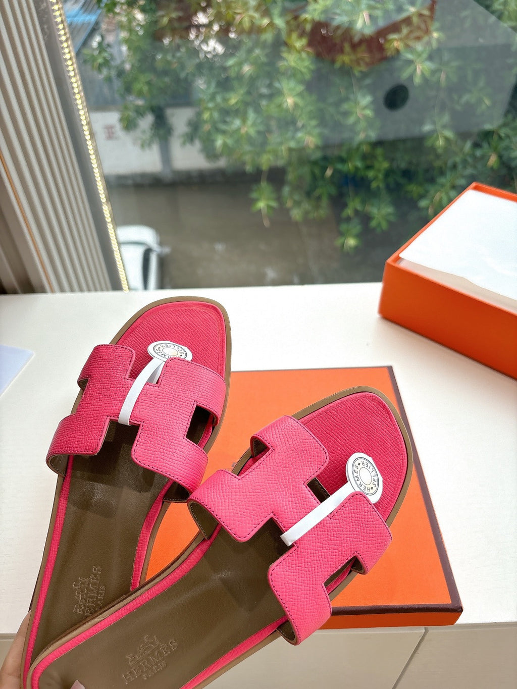 Pink leather slide sandals with two straps and circular emblem buckle, top view