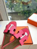 Pink leather slide sandals with two straps and circular emblem buckle, top view