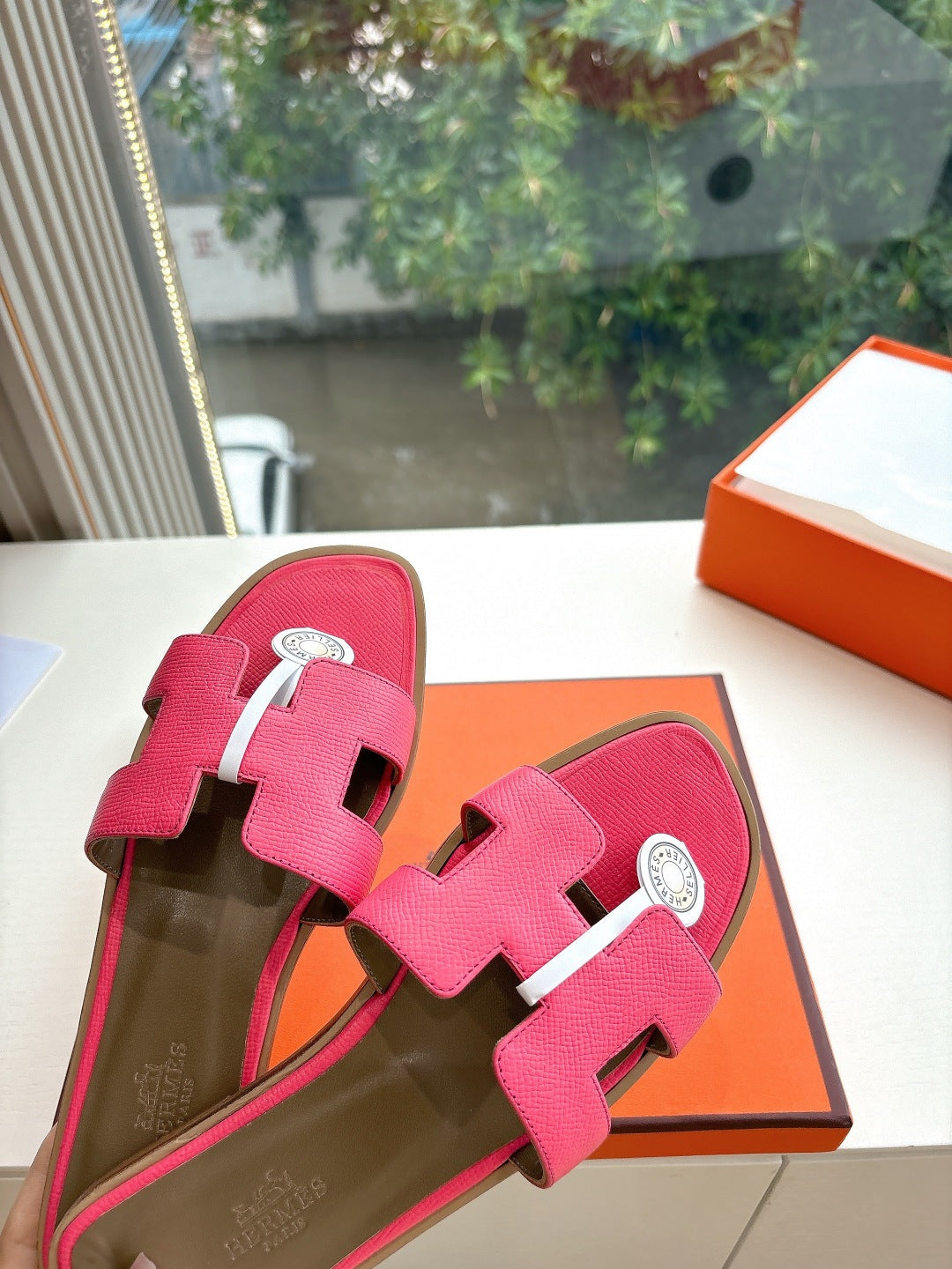Pink leather slide sandals with two straps and circular emblem buckle, top view