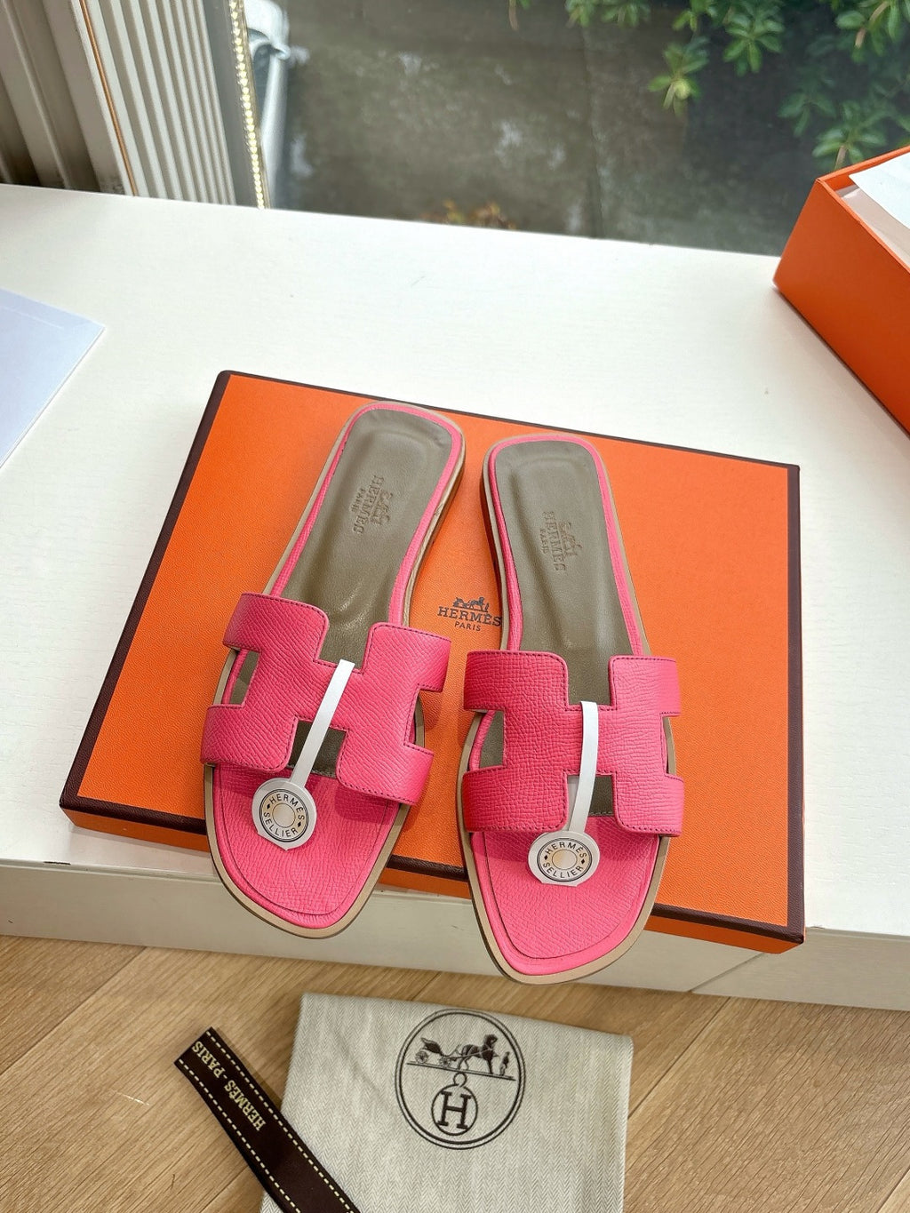 Pink slide sandals with silver-tone circular emblem and open toe, gift box