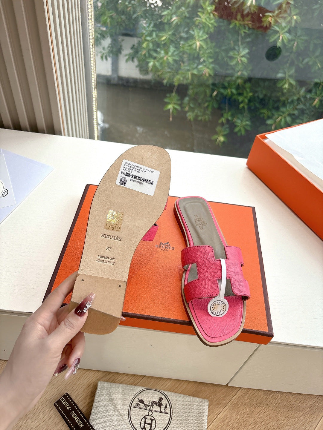 Hermes pink slide sandal showing underside beige sole with label tag, in box