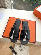 Hermes black leather slide sandals with front buckle straps and round logo medallions