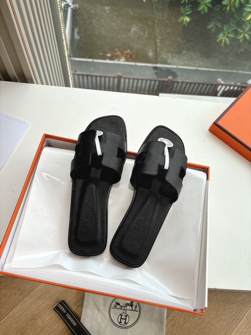 Hermes black slide sandals with wide toe straps and circular logo emblem