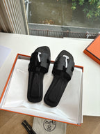 Hermes black slide sandals with wide toe straps and circular logo emblem