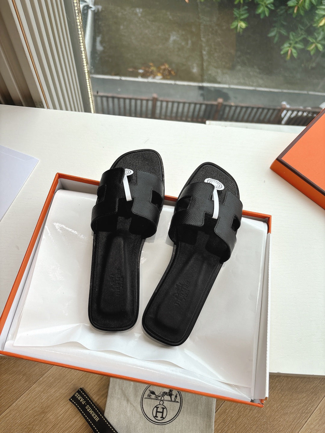 Hermes black slide sandals with wide toe straps and circular logo emblem