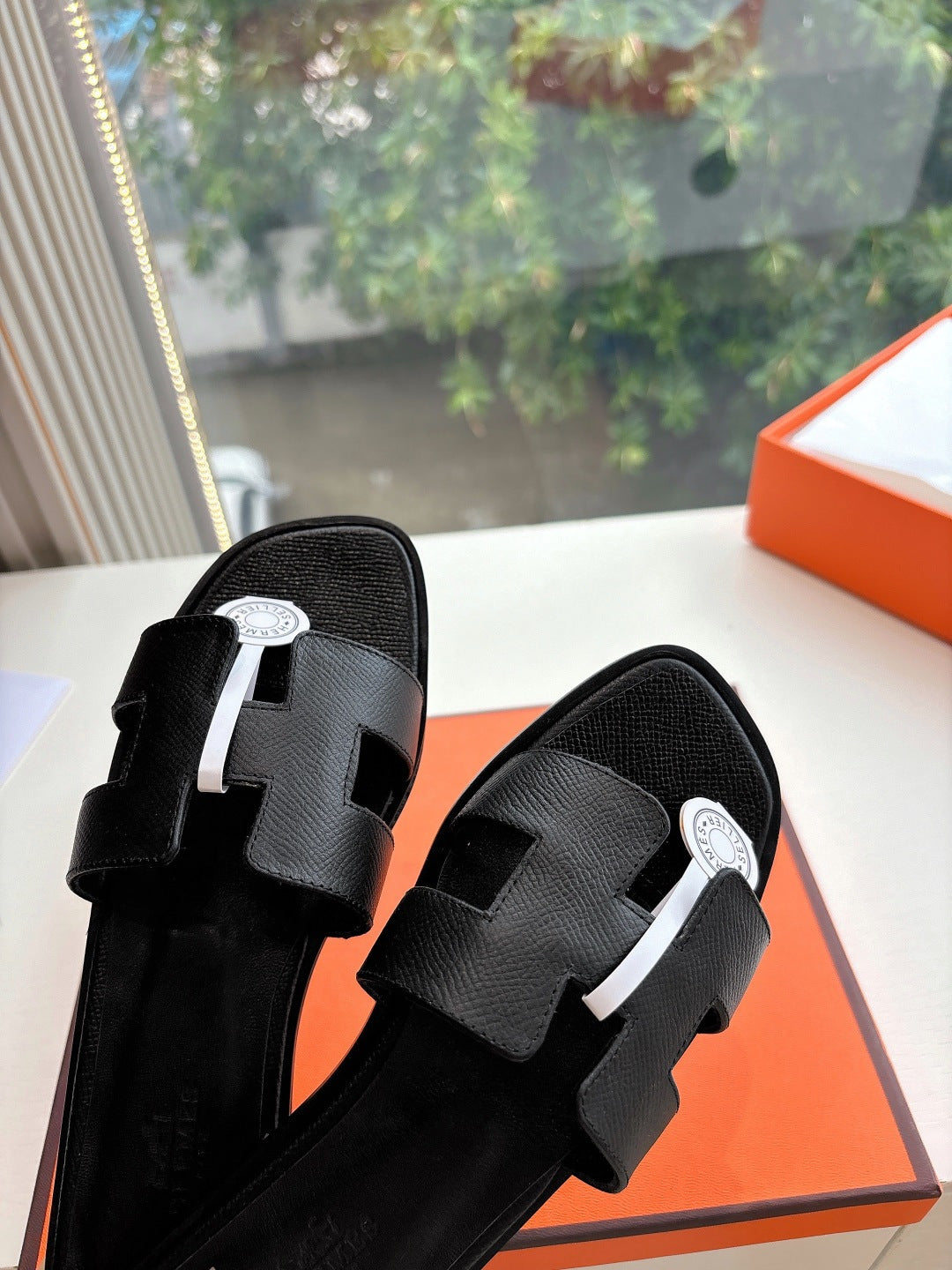 Hermes black leather slide sandals with textured straps and circular logo hardware