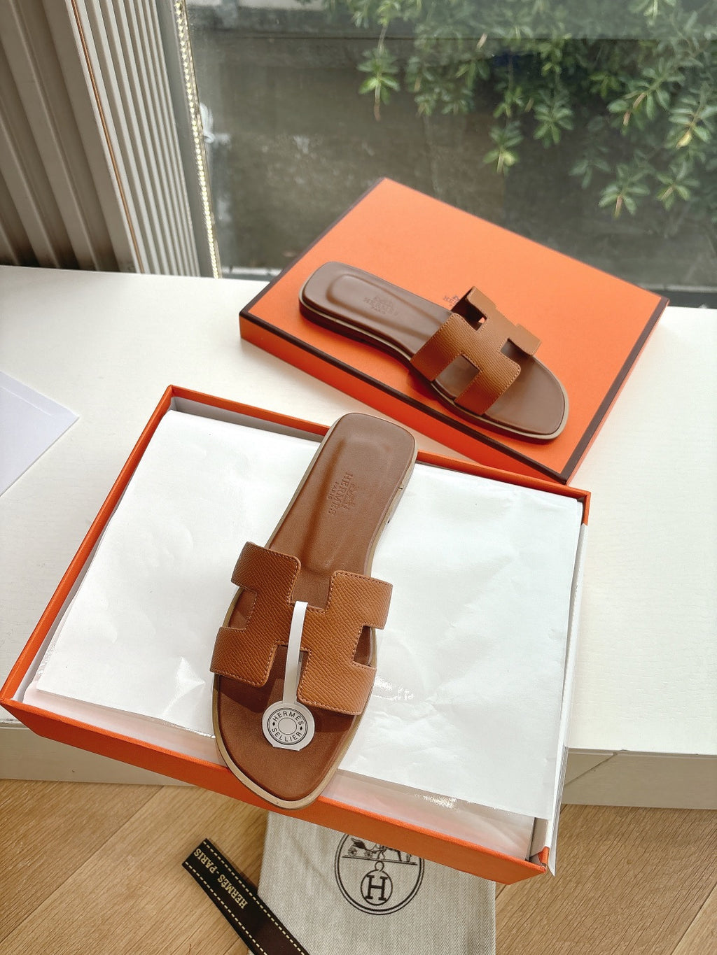 Hermes tan slip-on sandals with geometric strap cutouts and round logo medallion