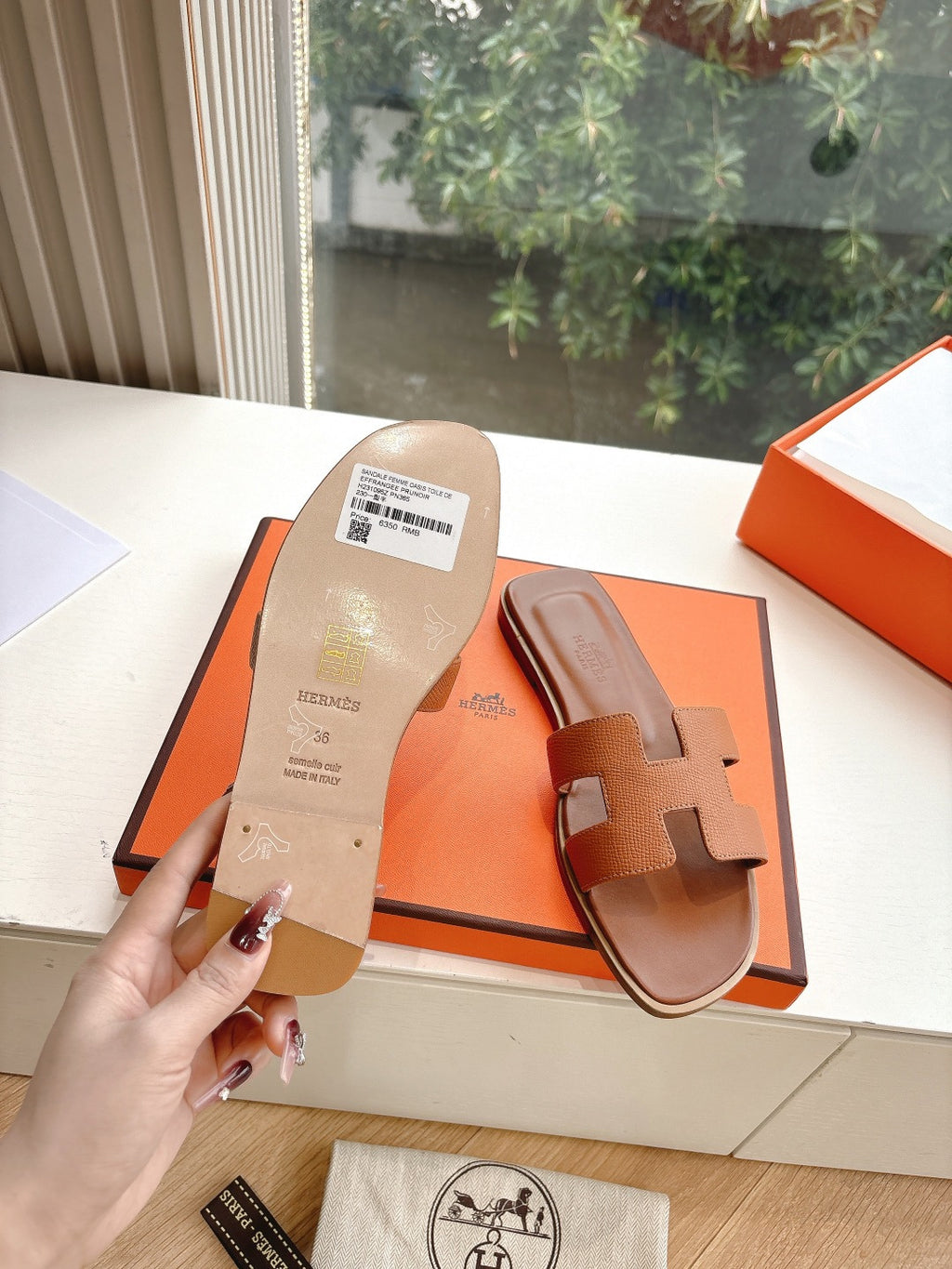 Hermes tan slide sandals showing the printed sole and geometric strap cutouts