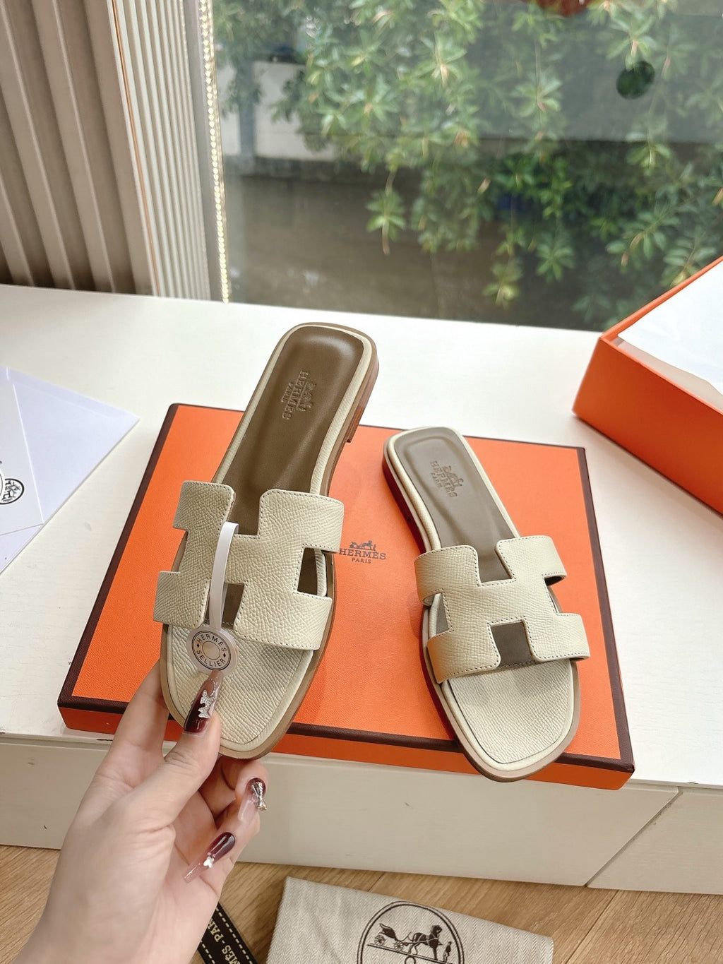 Hermes slide sandals in light beige with circular logo charm on front strap